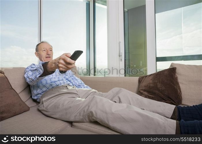Senior man watching TV on sofa at home