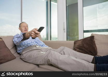 Senior man watching TV on sofa at home