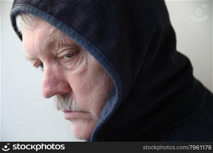 senior man wearing a dark jacket with hood