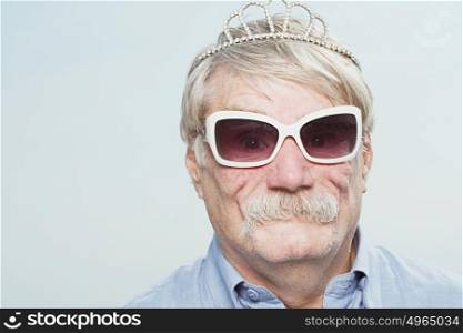 Senior man wearing a tiara and sunglasses