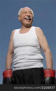 Senior man wearing boxing gloves and smiling