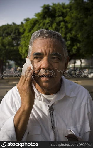 Senior man wiping face, outdoors