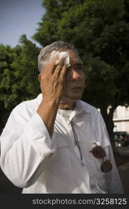 Senior man wiping face, outdoors