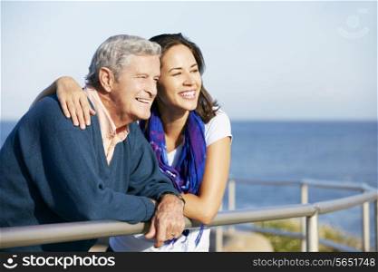Senior Man With Adult Daughter Looking Over Railing At Sea