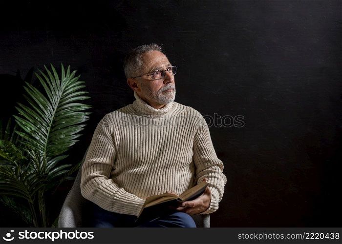 senior man with book looking away