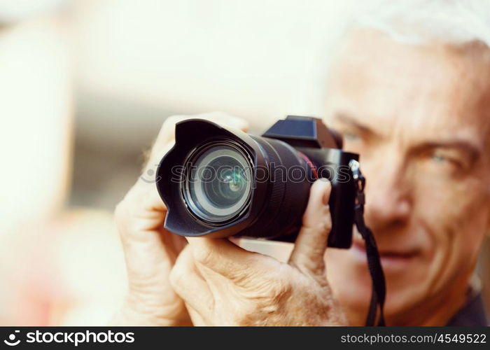 Senior man with camera in city. Looking for good shoots