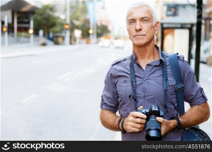 Senior man with camera in city. Looking for good shoots