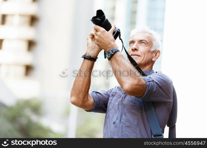 Senior man with camera in city. Looking for good shoots