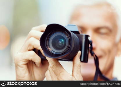 Senior man with camera in city. Looking for good shoots