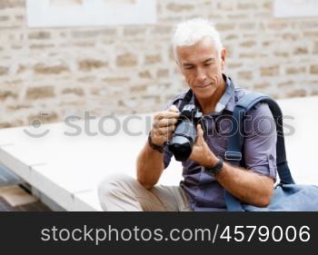 Senior man with camera in city. Looking for good shoots