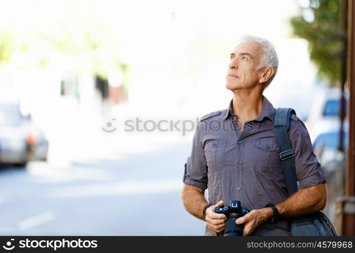 Senior man with camera in city. Looking for good shoots