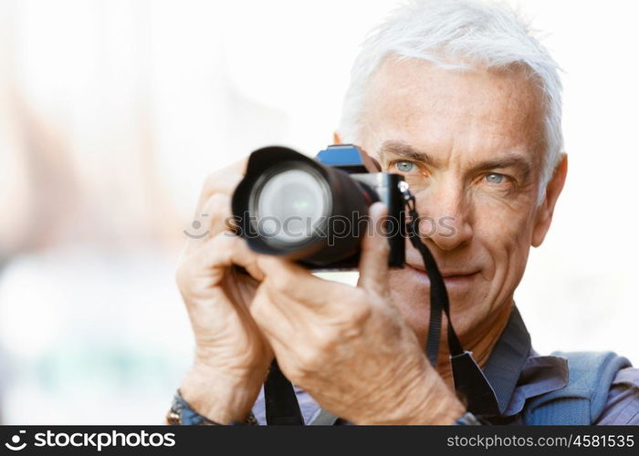 Senior man with camera in city. Looking for good shoots