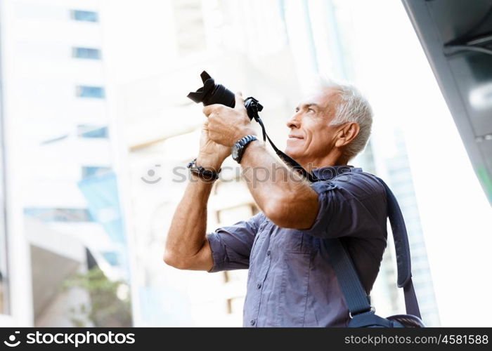 Senior man with camera in city. Looking for good shoots