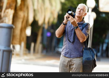 Senior man with camera in city. Looking for good shoots