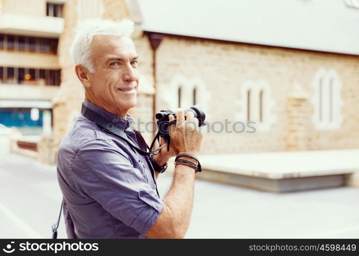 Senior man with camera in city. Looking for good shoots