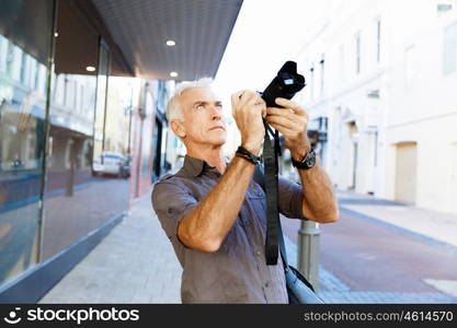 Senior man with camera in city. Looking for good shoots