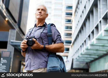 Senior man with camera in city. Looking for good shoots