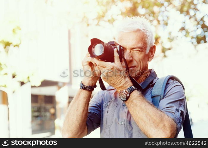 Senior man with camera in city. Looking for good shoots