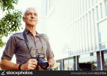 Senior man with camera in city. Looking for good shoots