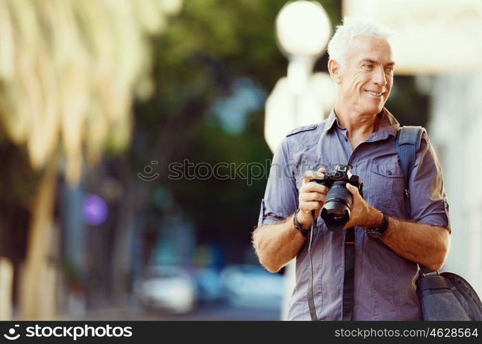 Senior man with camera in city. Looking for good shoots