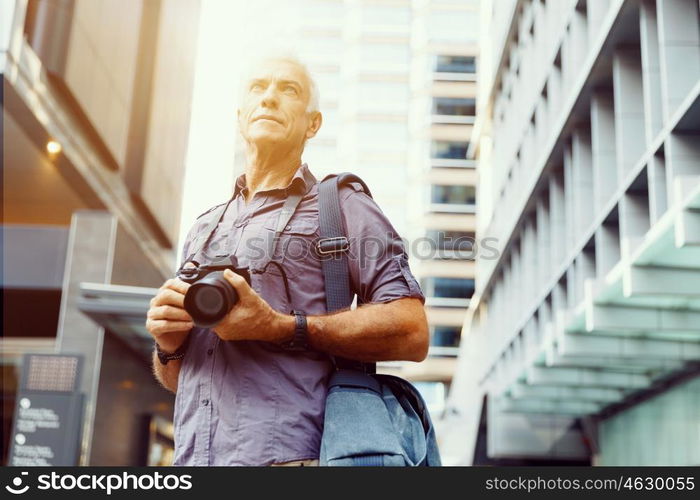 Senior man with camera in city. Looking for good shoots