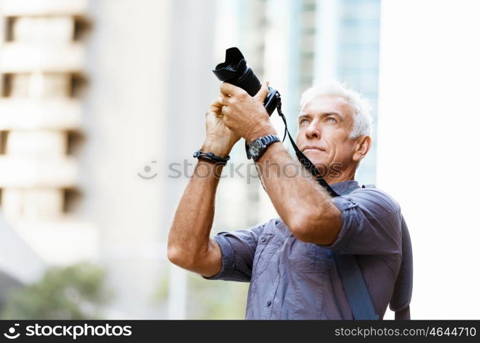 Senior man with camera in city. Looking for good shoots