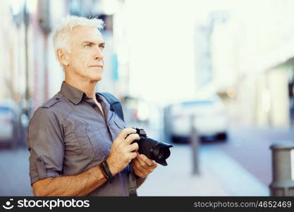 Senior man with camera in city. Looking for good shoots