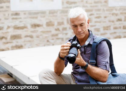 Senior man with camera in city. Looking for good shoots