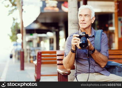 Senior man with camera in city. Looking for good shoots