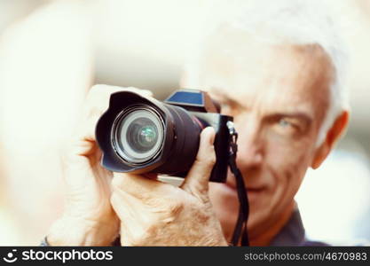 Senior man with camera in city. Looking for good shoots