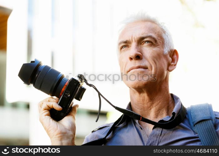 Senior man with camera in city. Looking for good shoots