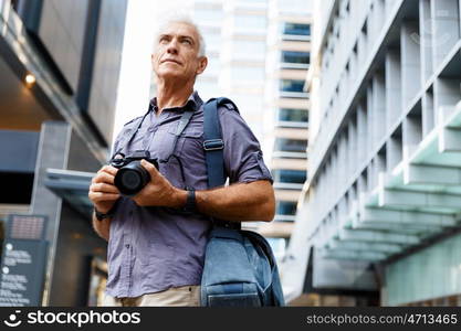 Senior man with camera in city. Looking for good shoots