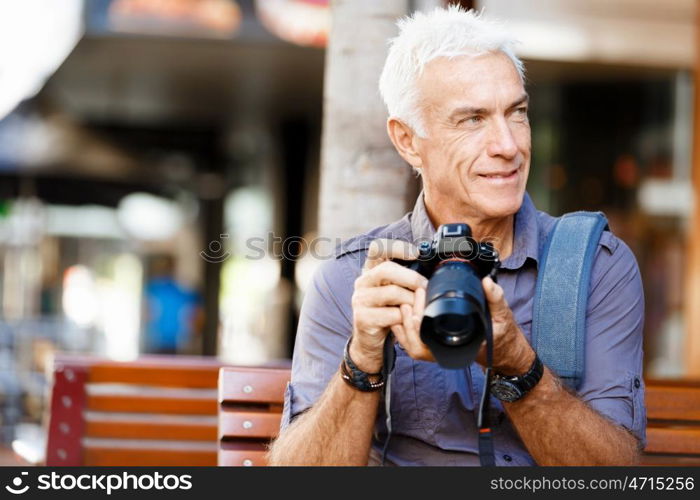 Senior man with camera in city. Looking for good shoots