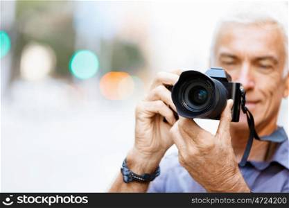 Senior man with camera in city. Looking for good shoots