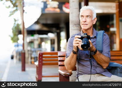 Senior man with camera in city. Looking for good shoots