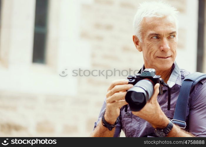 Senior man with camera in city. Looking for good shoots