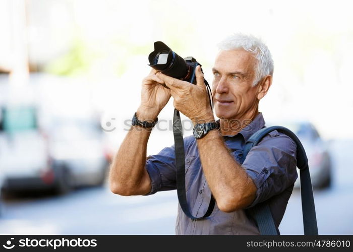 Senior man with camera in city. Looking for good shoots