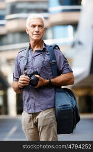 Senior man with camera in city. Looking for good shoots