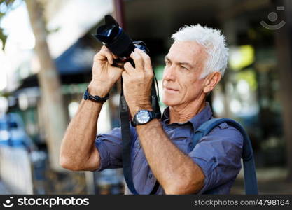 Senior man with camera in city. Looking for good shoots