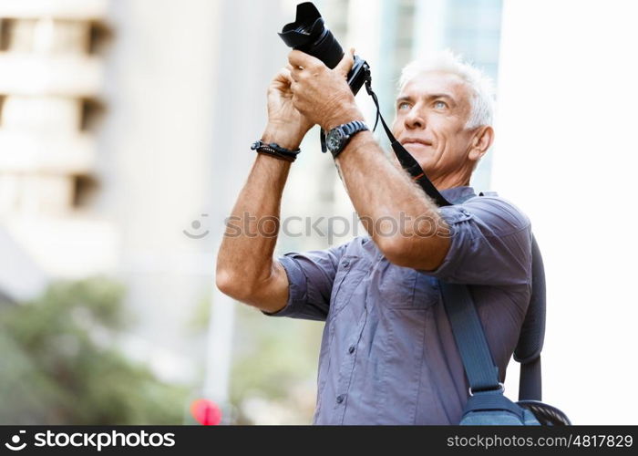 Senior man with camera in city. Looking for good shoots