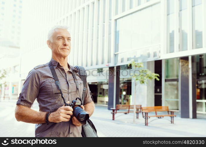 Senior man with camera in city. Looking for good shoots