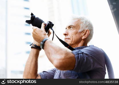 Senior man with camera in city. Looking for good shoots