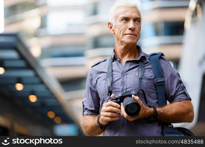 Senior man with camera in city. Looking for good shoots