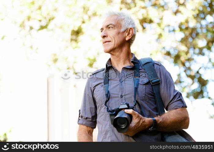 Senior man with camera in city. Looking for good shoots