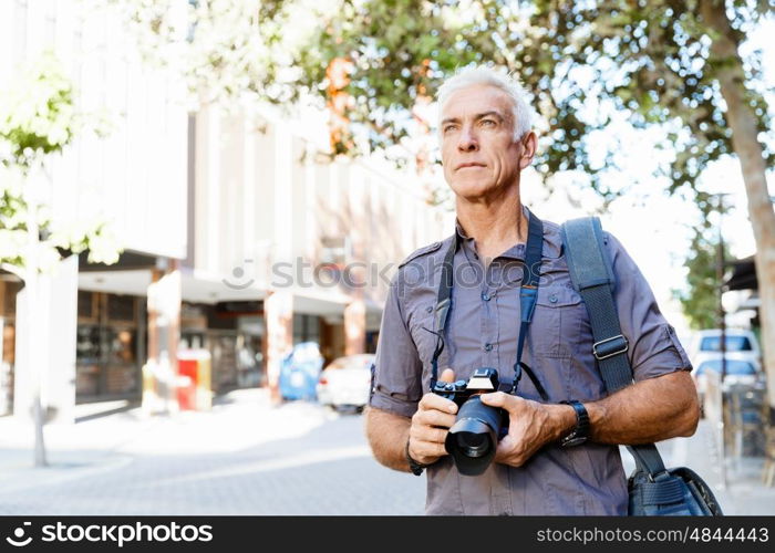 Senior man with camera in city. Looking for good shoots