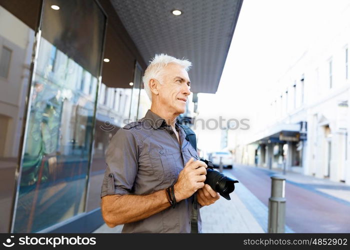 Senior man with camera in city. Looking for good shoots