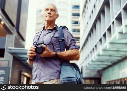 Senior man with camera in city. Looking for good shoots