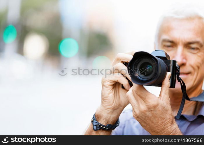 Senior man with camera in city. Looking for good shoots