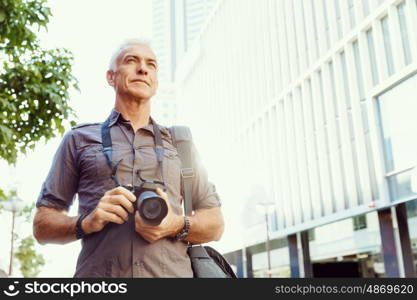 Senior man with camera in city. Looking for good shoots