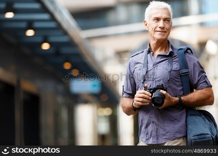 Senior man with camera in city. Looking for good shoots